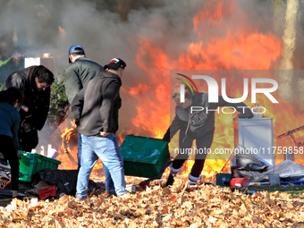 People try to recover belongings from a fire that engulfs tents at a homeless encampment in Gage Park, in Hamilton, Ontario, on November 9,...