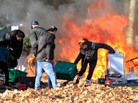 People try to recover belongings from a fire that engulfs tents at a homeless encampment in Gage Park, in Hamilton, Ontario, on November 9,...