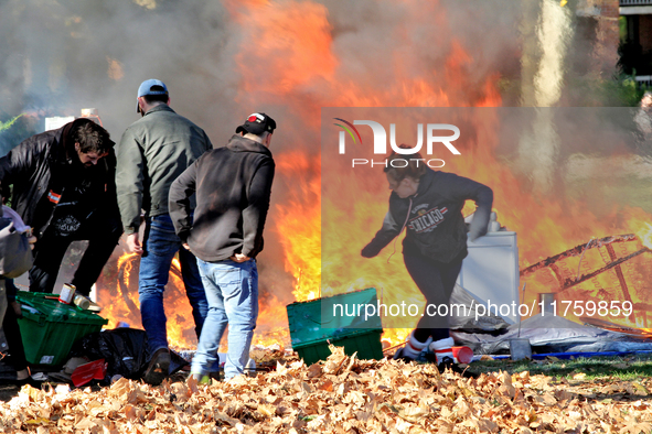 People try to recover belongings from a fire that engulfs tents at a homeless encampment in Gage Park, in Hamilton, Ontario, on November 9,...