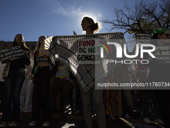 An activist holds a traditional Palestinian Keffiyeh with ''Fund DC not Genocide'' written on it while joining a demonstration. (