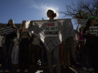 An activist holds a traditional Palestinian Keffiyeh with ''Fund DC not Genocide'' written on it while joining a demonstration. (