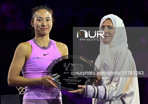 RIYADH, SAUDI ARABIA - NOVEMBER 09: Qinwen Zheng of China poses with the runner-up trophy alongside Saudi Tennis Federation president Arij M...