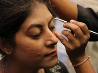 A model gets her makeup done before taking to the runway during a fashion show organized by Lions International in JW Marriott, Kolkata, Ind...