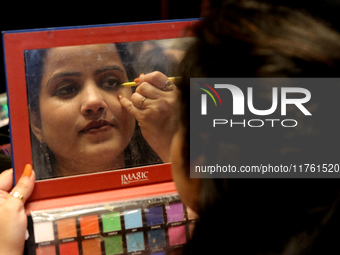 A model gets her makeup done before taking to the runway during a fashion show organized by Lions International in JW Marriott, Kolkata, Ind...