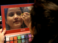 A model gets her makeup done before taking to the runway during a fashion show organized by Lions International in JW Marriott, Kolkata, Ind...