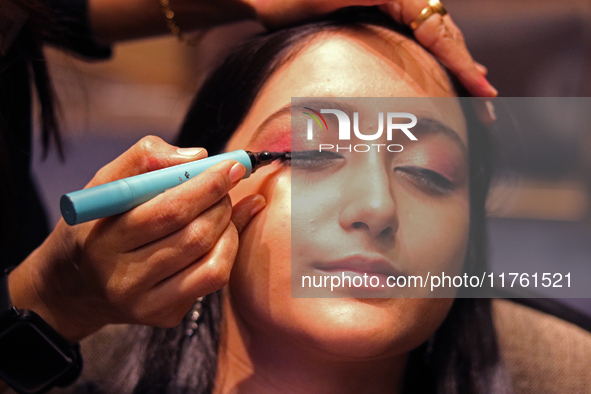 A model gets her makeup done before taking to the runway during a fashion show organized by Lions International in JW Marriott, Kolkata, Ind...