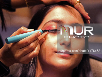 A model gets her makeup done before taking to the runway during a fashion show organized by Lions International in JW Marriott, Kolkata, Ind...