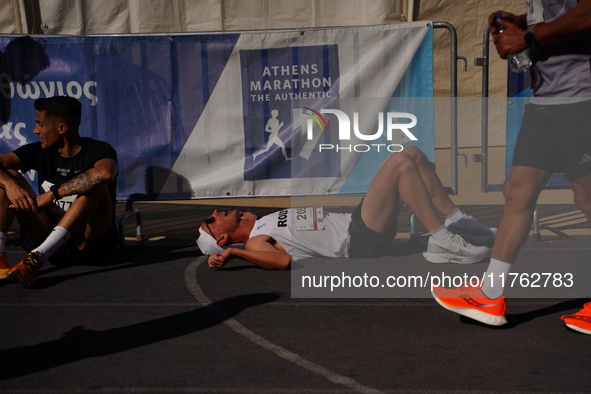 A marathon runner lies on the ground immediately after finishing the Athens Marathon in Athens, Greece, on November 10, 2024 