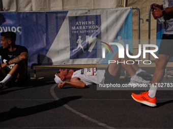 A marathon runner lies on the ground immediately after finishing the Athens Marathon in Athens, Greece, on November 10, 2024 (