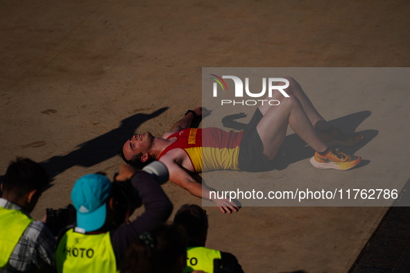 A marathon runner lies on the ground immediately after finishing the Athens Marathon in Athens, Greece, on November 10, 2024 