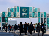 Participants walk by an entrance of COP29, UN Climate Change Conference venue, an event held by UNFCCC in Baku Olympic Stadium in Baku, the...