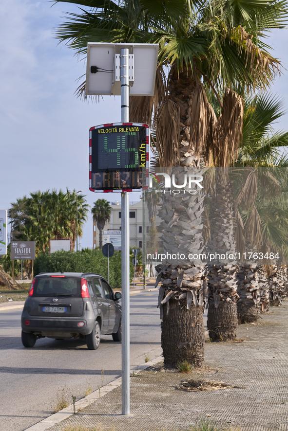 A solar-powered speed indicator installed along a palm-lined road aims to promote safe driving by monitoring and displaying vehicle speeds....