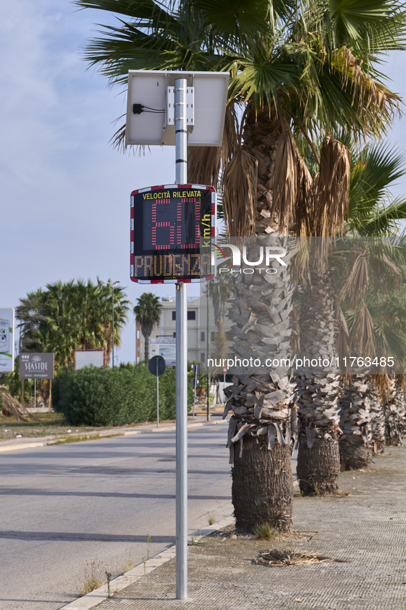 A solar-powered speed indicator installed along a palm-lined road aims to promote safe driving by monitoring and displaying vehicle speeds....