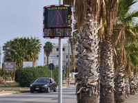 A solar-powered speed indicator installed along a palm-lined road aims to promote safe driving by monitoring and displaying vehicle speeds....