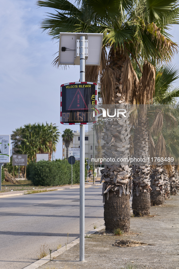 A solar-powered speed indicator installed along a palm-lined road aims to promote safe driving by monitoring and displaying vehicle speeds....