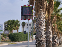 A solar-powered speed indicator installed along a palm-lined road aims to promote safe driving by monitoring and displaying vehicle speeds....