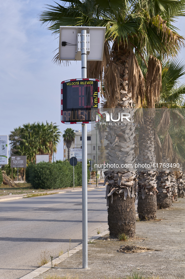 A solar-powered speed indicator installed along a palm-lined road aims to promote safe driving by monitoring and displaying vehicle speeds....