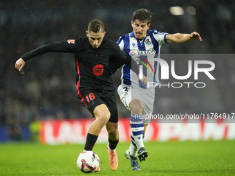 Fermin Lopez central midfield of Barcelona and Spain and Aihen Munoz left-back of Real Sociedad and Spain compete for the ball during the La...