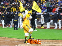 The Las Aguilas Cibaenas mascot celebrates with a stuffed tiger after the team's 3-2 win in the baseball game against Los Tigres del Licey a...