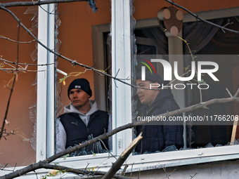 Men stand on the balcony of a residential building damaged by the Russian drone attack in the Khadzhybeiskyi district of Odesa, Ukraine, on...