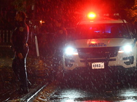 NYPD police officers guard the crime scene as heavy rainfall ends the rainless drought streak. A 16-year-old boy is shot in the East Flatbus...