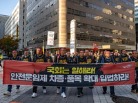 Members of the Cargo Truckers Solidarity Division of the Korean Public Service and Transport Workers' Union under the KCTU march near the Na...