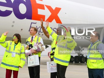 FedEx employees and crew members wave to people as they greet them in Qingdao, China, on November 11, 2024. (