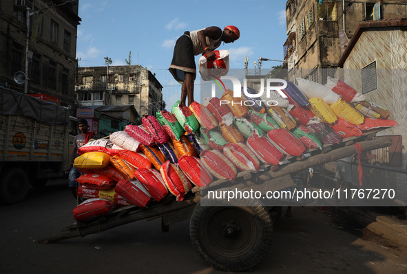 A laborer carries a load of consumer goods onto a supply cart at a wholesale market in Kolkata, India, on November 11, 2024. India's consume...