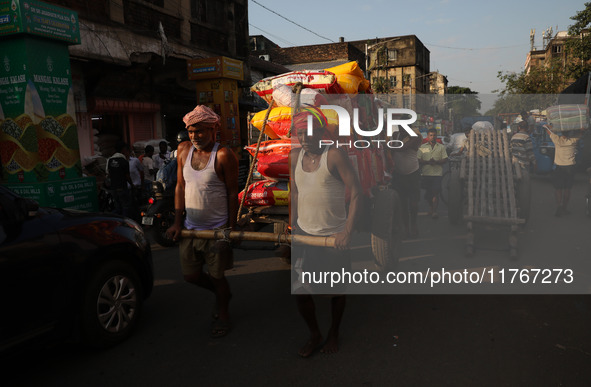 Labourers pull a cart after loading consumer goods onto a supply cart at a wholesale market in Kolkata, India, on November 11, 2024. India's...