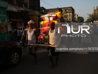 Labourers pull a cart after loading consumer goods onto a supply cart at a wholesale market in Kolkata, India, on November 11, 2024. India's...