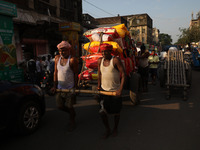 Labourers pull a cart after loading consumer goods onto a supply cart at a wholesale market in Kolkata, India, on November 11, 2024. India's...