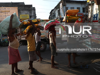 Labourers load consumer goods onto supply trucks at a wholesale market in Kolkata, India, on November 11, 2024. India's consumer price infla...