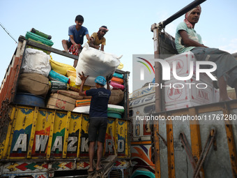 Labourers load consumer goods onto supply trucks at a wholesale market in Kolkata, India, on November 11, 2024. India's consumer price infla...