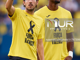 Dani Parejo of Villarreal CF wears a t-shirt supporting the victims of the Valencia floodings and waves his hand next to his teammate Logan...