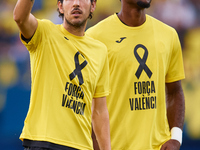 Dani Parejo of Villarreal CF wears a t-shirt supporting the victims of the Valencia floodings and waves his hand next to his teammate Logan...