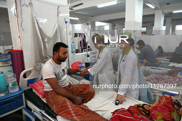 A nurse treats a patient covered with mosquito nets suffering from dengue fever inside the 'Shaheed Suhrawardy' Medical College Hospital in...