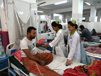 A nurse treats a patient covered with mosquito nets suffering from dengue fever inside the 'Shaheed Suhrawardy' Medical College Hospital in...