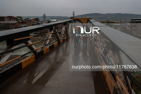 People walk on a bridge during rainfall in Baramulla, Jammu and Kashmir, India, on November 11, 2024. 