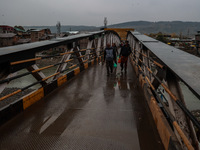 People walk on a bridge during rainfall in Baramulla, Jammu and Kashmir, India, on November 11, 2024. (