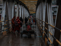 People walk on a bridge during rainfall on a winter day in Baramulla, Jammu and Kashmir, India, on November 11, 2024. (