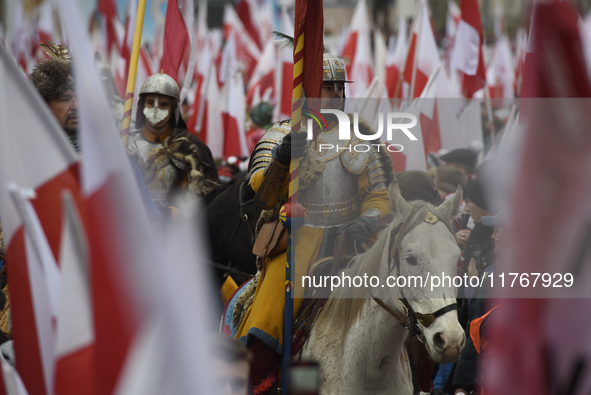 People watch a rehearsal group on horseback and wave Poland's national flags as they participate in the 106th anniversary of Poland regainin...