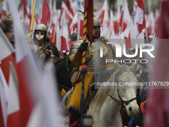 People watch a rehearsal group on horseback and wave Poland's national flags as they participate in the 106th anniversary of Poland regainin...