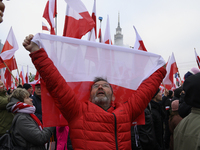 A man holds a national flag of Poland as he participates in the 106th anniversary of Poland's regaining its independence in Warsaw, Poland,...