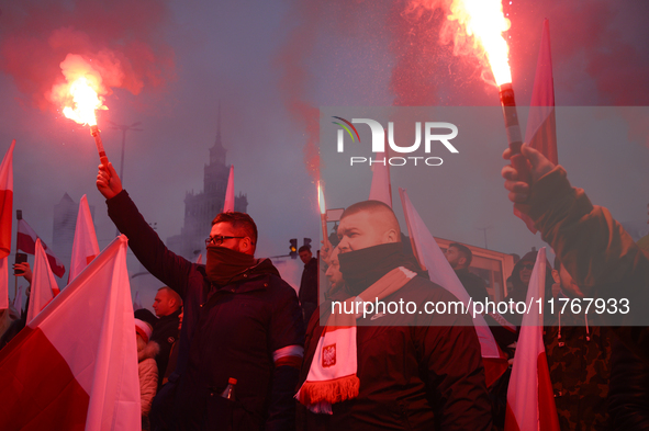 People hold flares as they participate in the 106th anniversary of Poland regaining its independence in Warsaw, Poland, on November 11, 2023...