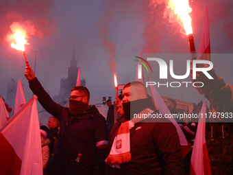 People hold flares as they participate in the 106th anniversary of Poland regaining its independence in Warsaw, Poland, on November 11, 2023...