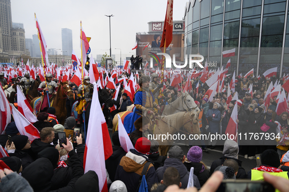 People watch a rehearsal group on horseback and wave Poland's national flags as they participate in the 106th anniversary of Poland regainin...