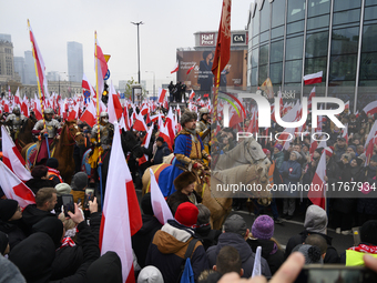 People watch a rehearsal group on horseback and wave Poland's national flags as they participate in the 106th anniversary of Poland regainin...