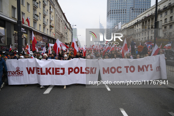 People carry a banner that reads ''We are Greater Poland's Power'' and wave white-red flags as they participate in the 106th anniversary of...