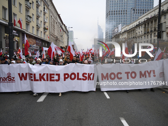 People carry a banner that reads ''We are Greater Poland's Power'' and wave white-red flags as they participate in the 106th anniversary of...