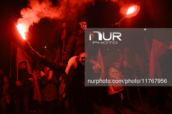 People hold lit flares as they take part in the 106th anniversary of Poland regaining its independence in Warsaw, Poland, on November 11, 20...